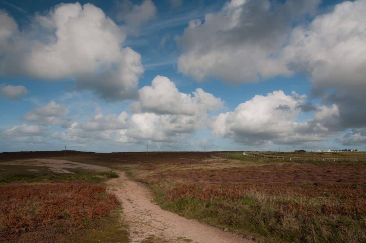 Fluffy clouds and the walking path at Les Landes, St. Ouen