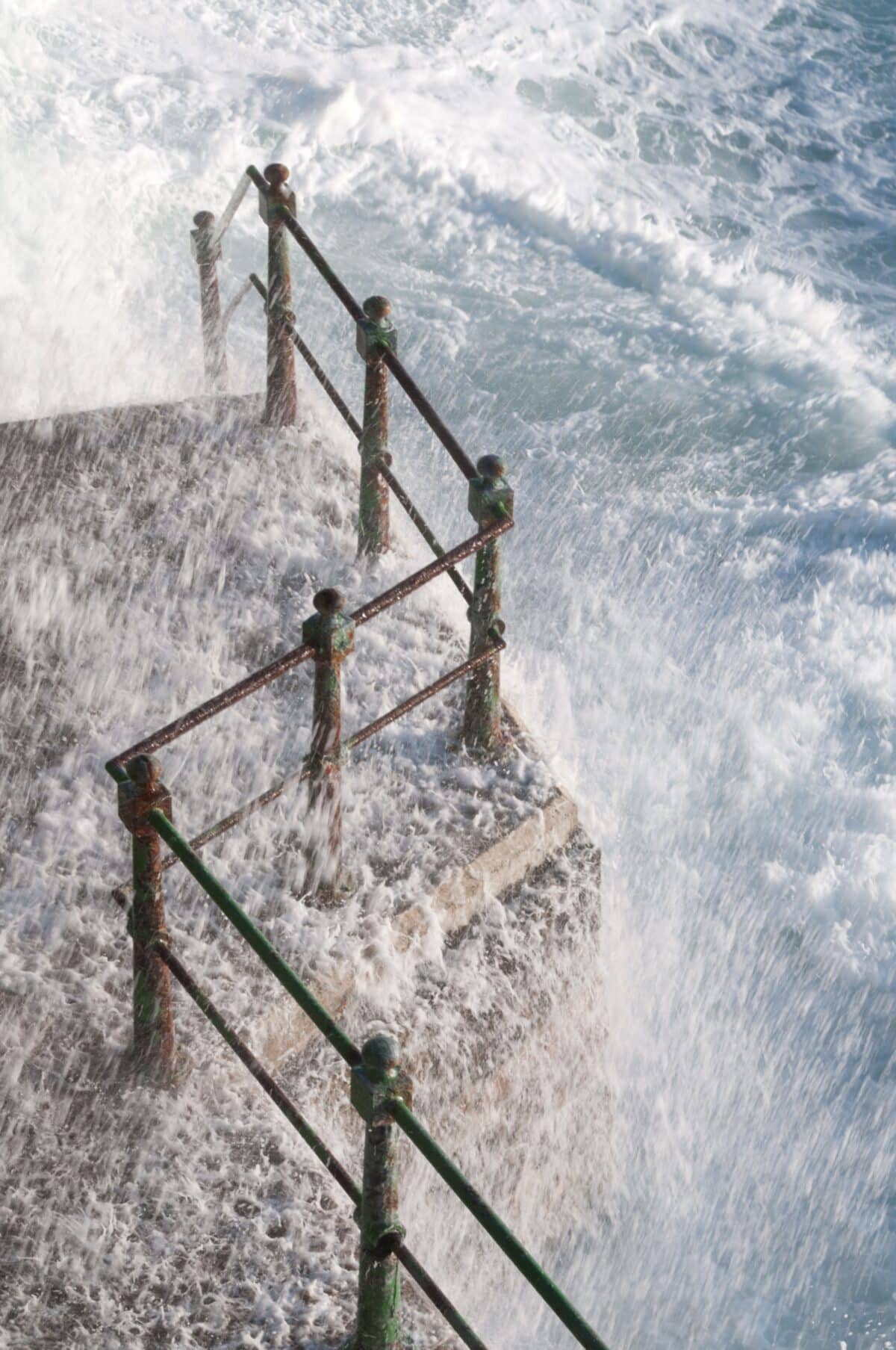 High tide splashing over the railings at L'Ouzière Slip
