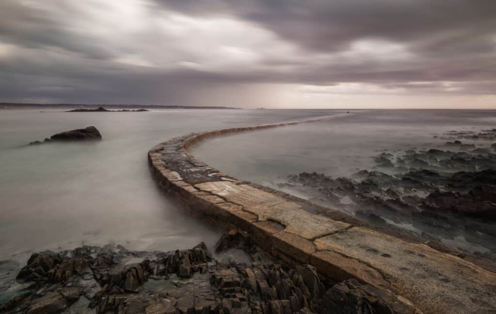 Tide rising over the jetty at L'Etacq on a grey day, St. Ouen