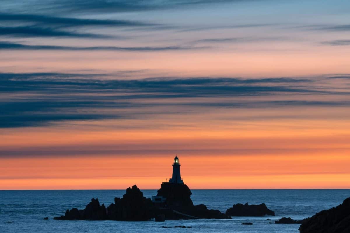 Vibrant sunset silhouette of illuminated Corbière Lighthouse