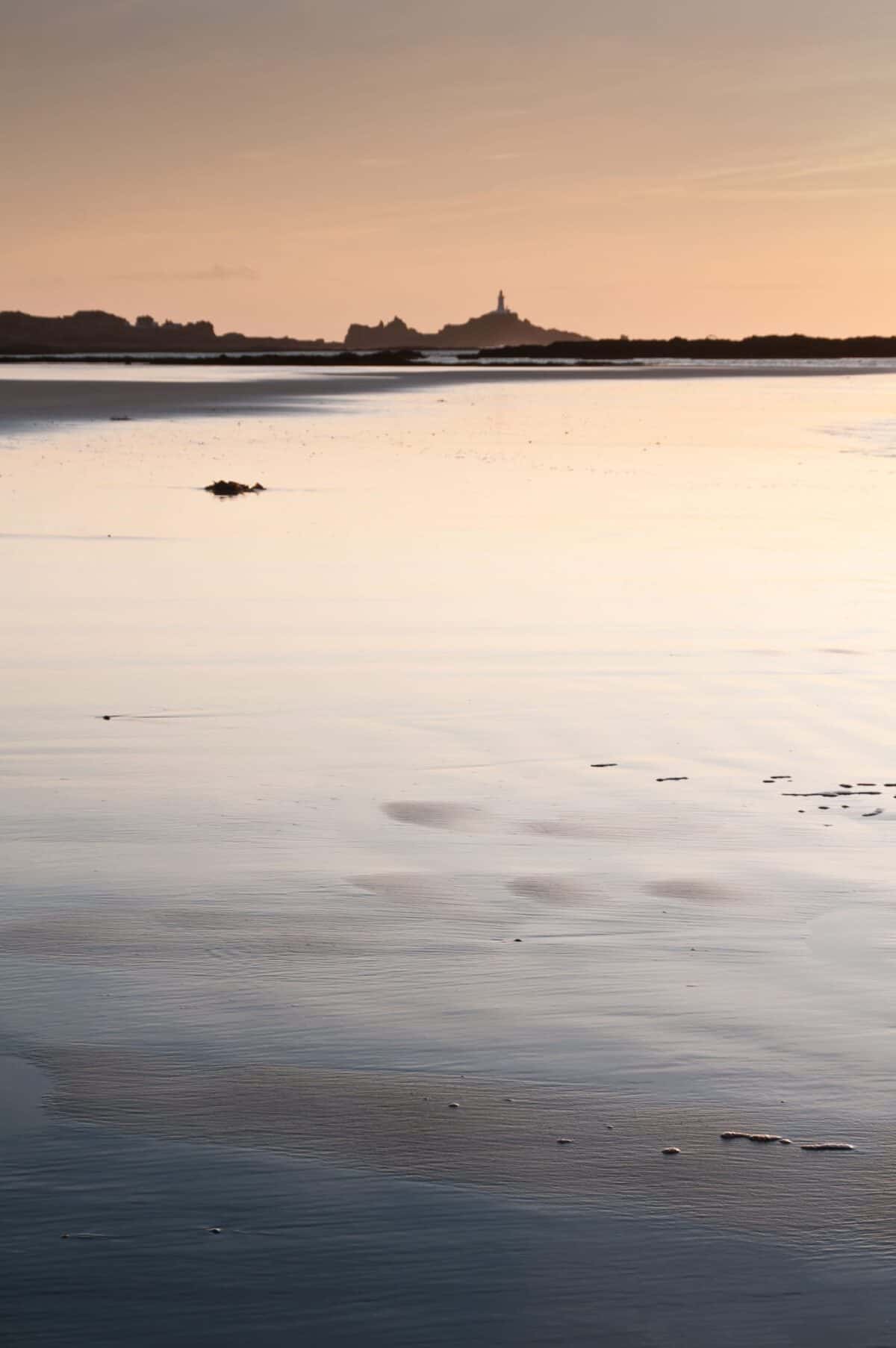 Sunset silver reflection on wet sand, with Corbière Lighthouse
