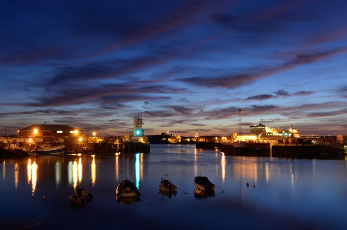 Sunset lights at St. Helier Harbour w/ control tower and castle