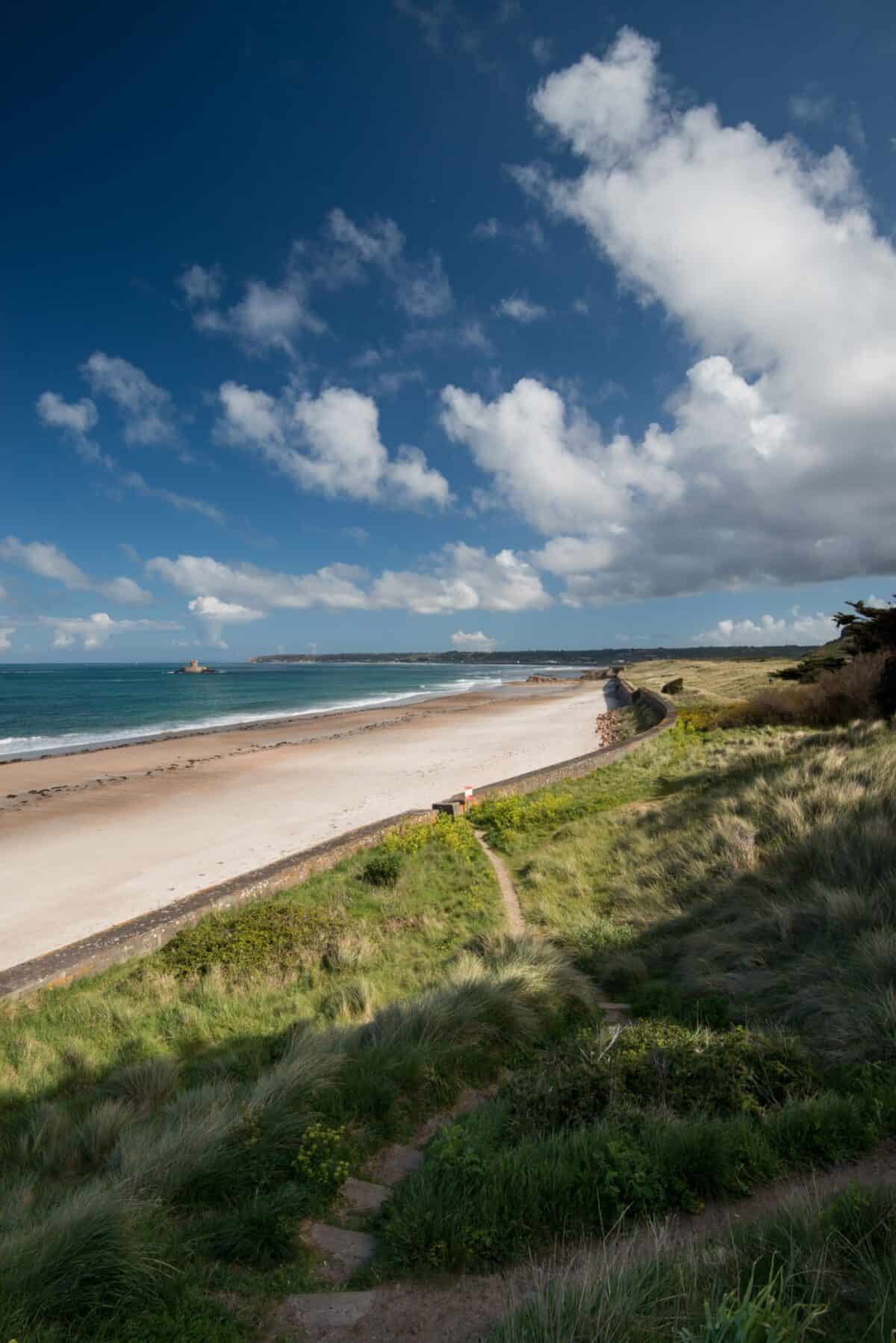 Beach at La Pulente with blue sky and fluffy clouds, St. Brelade