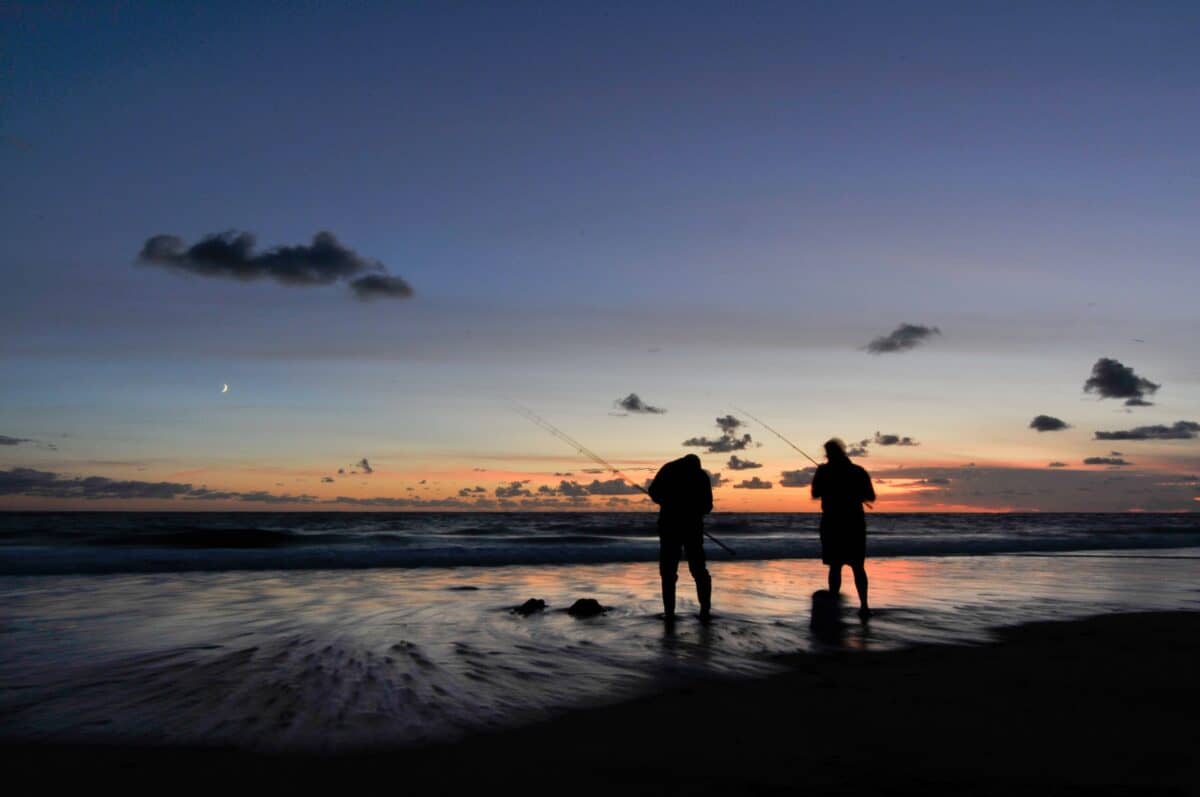 Two fisherman on the beach at sunset at St. Ouen's Bay, St. Ouen